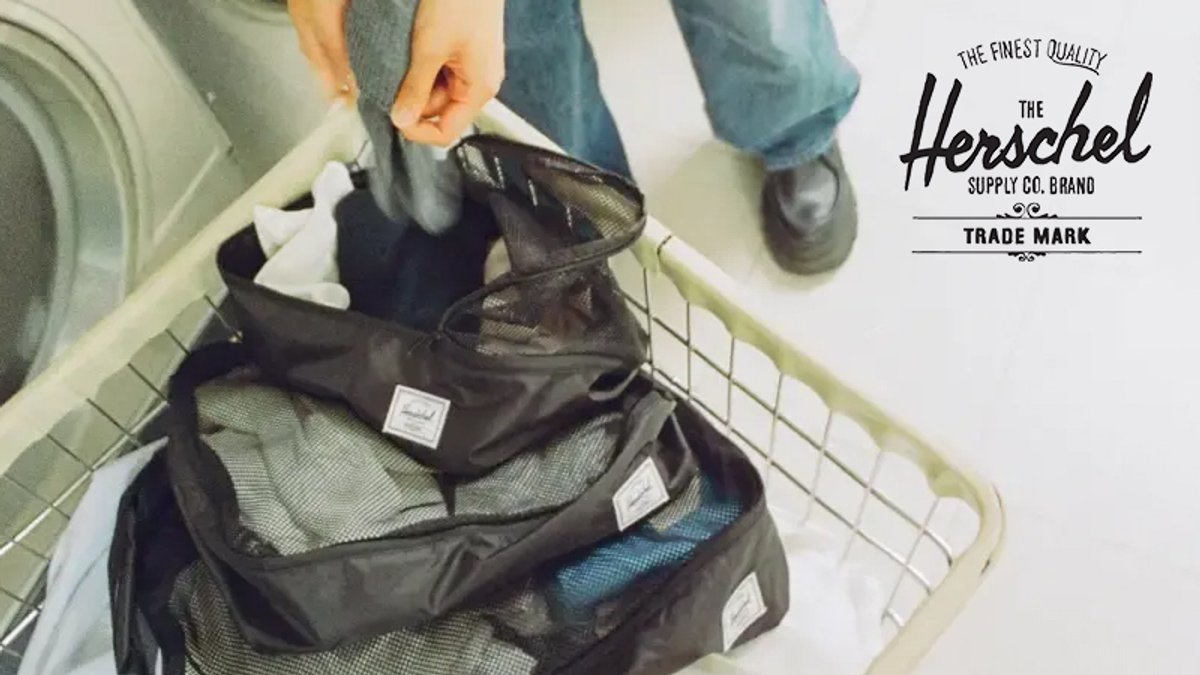 Herschel Supply packing cubes organized in a white laundry basket displaying mesh compartments and branded labels for efficient travel gear storage.
