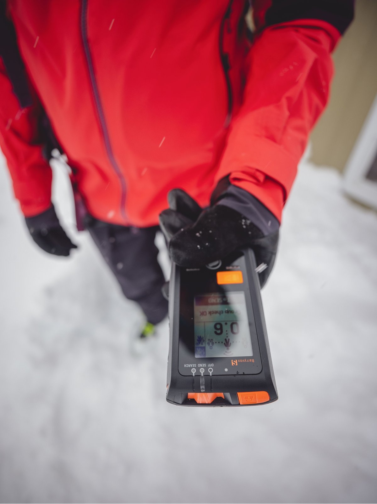 A person wearing a red jacket holds out a beacon.