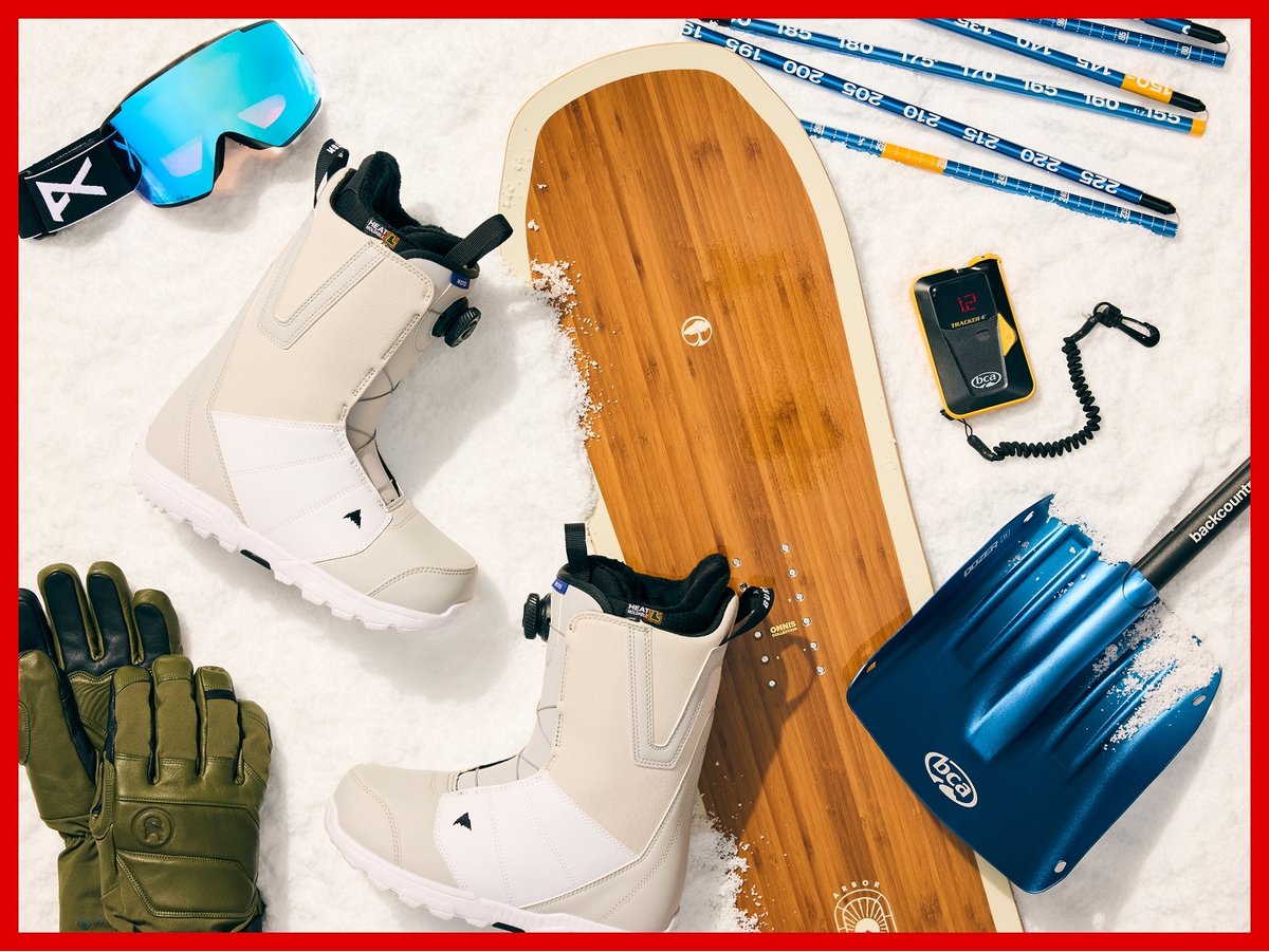 Snowboard gear on snow, including an Arbor board, Burton boots, Anon goggles, and a BCA shovel, probe, and beadon.