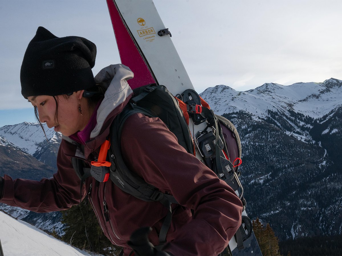 Skier bootpacking a snowy ridgeline with an avalanche airbag pack.