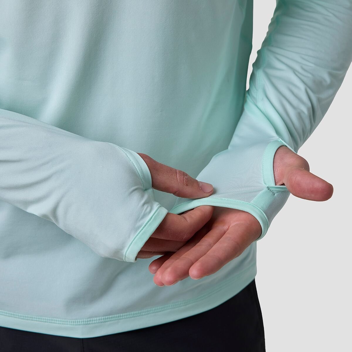 Persons hand and arms covered by Backcountry Tahoe Pro LT sun shirt with thumbs through thumbhole openings.