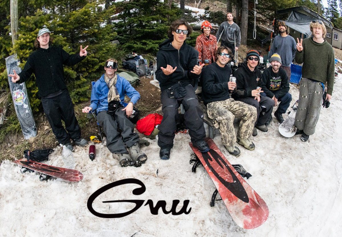 Group of snowboarders and skiers gathered in snowy mountain terrain with winter sports equipment, showcasing GNU snowboarding gear and winter sports lifestyle.