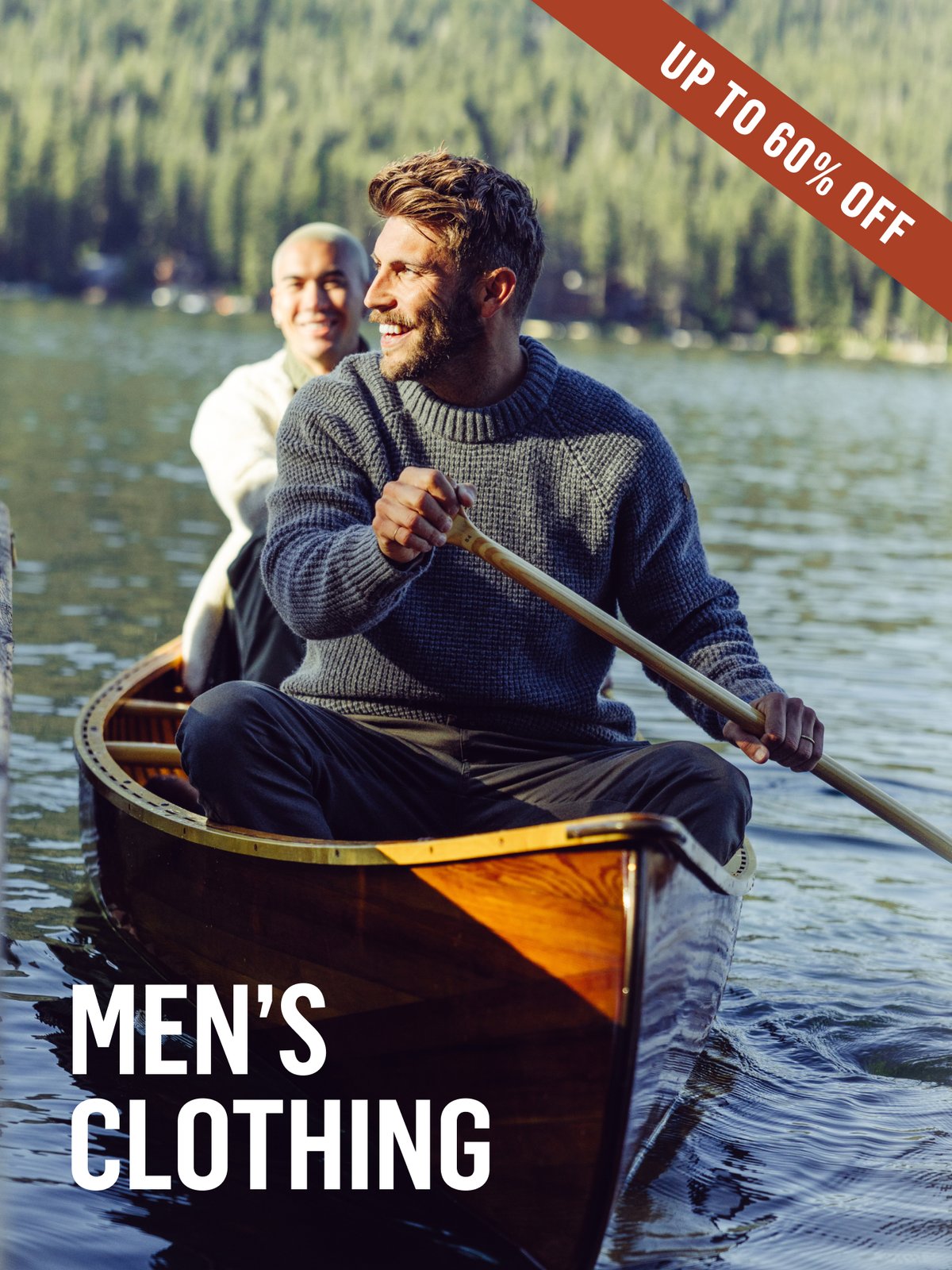 Two people paddling a wooden canoe across a calm mountain lake, wearing knit sweaters. Up to 60% off men's clothing.