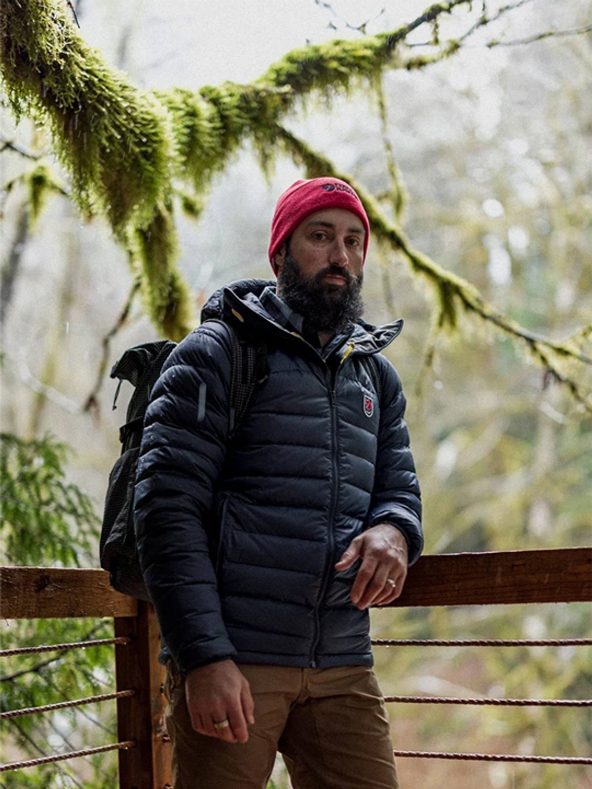 A man wears a Fjallraven Expedition jacket against a forest landscape.