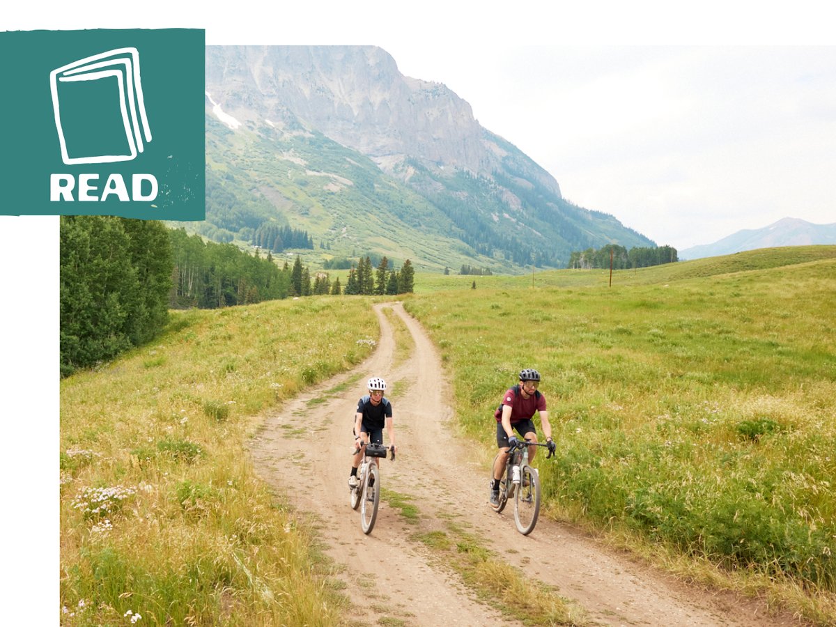 Two gravel riders in a large Colorado meadow.