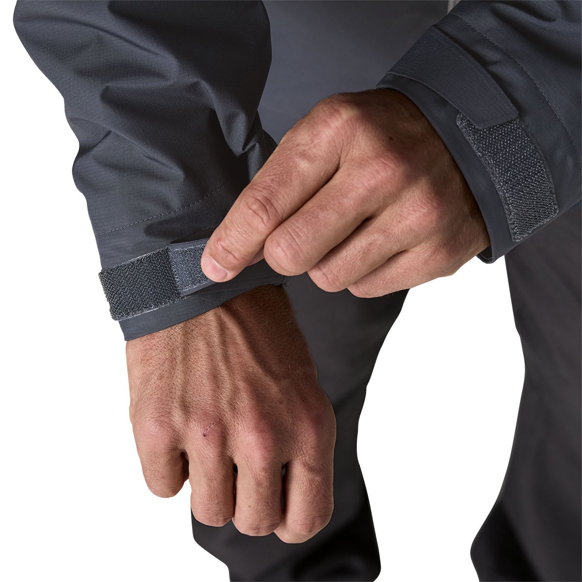 A closeup of a man adjusting his stormproof cuffs on the Insulated Boulder Fork Rain Jacket.