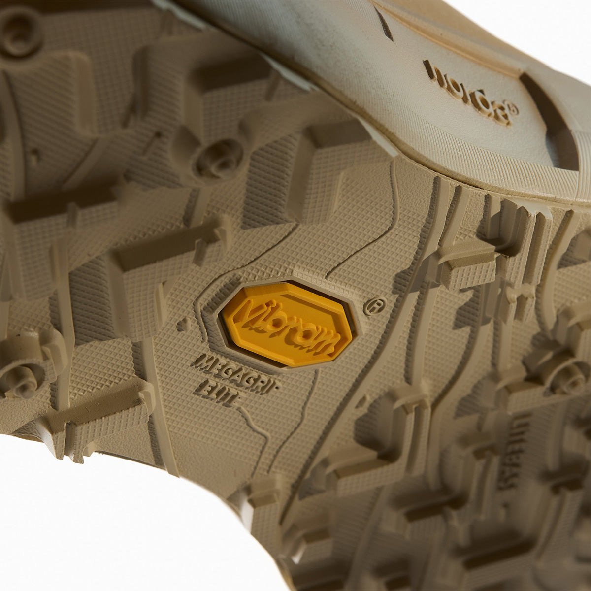 Angled view of the tan Norda outsole showing Vibram Megagrip Elite lug pattern with yellow Vibram logo and "Megagrip Elite" text molded in.