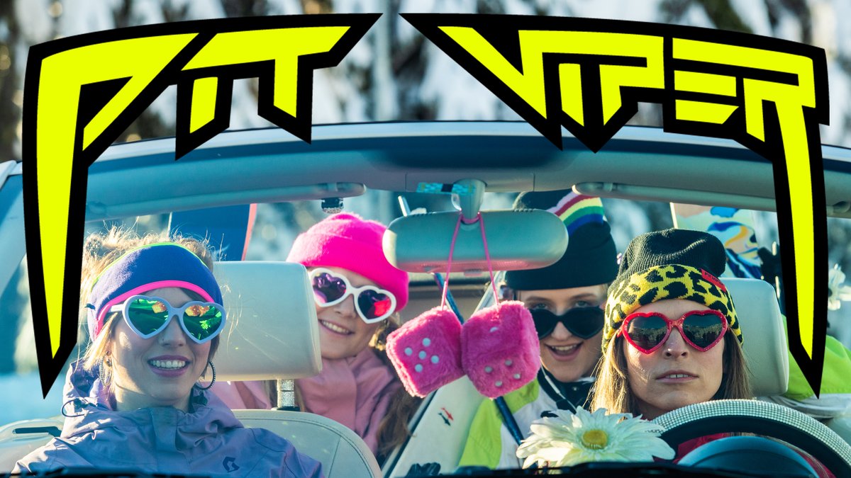 A group of four smiling young women wearing colorful heart-shaped sunglasses and beanies enjoy a convertible car ride with bright accessories and decorations.