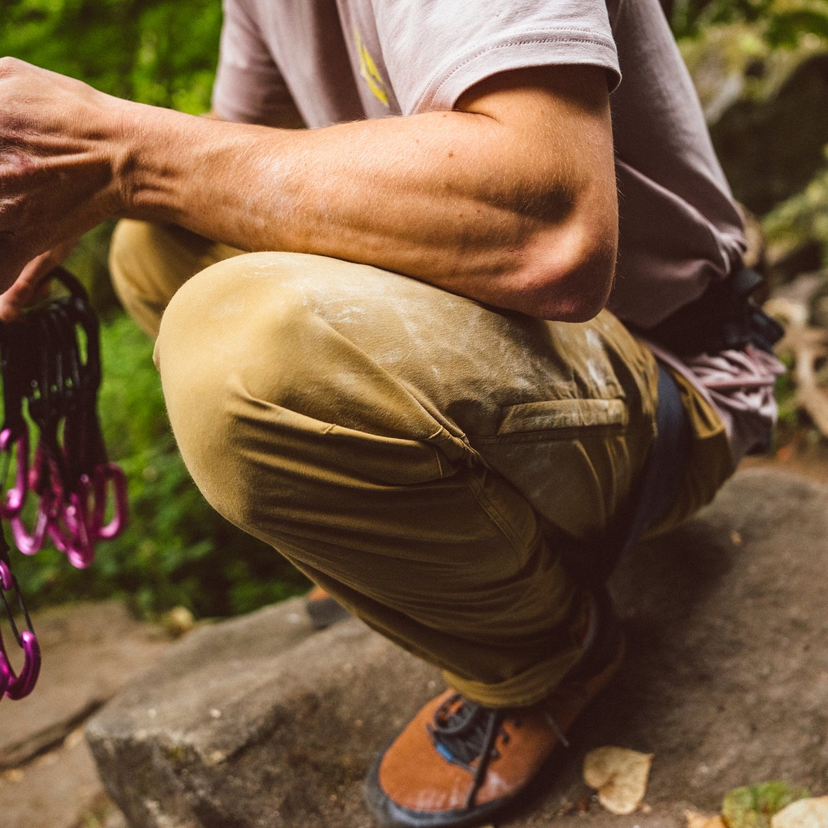 A sport climber squats in a clearly very stretchy pair of climbing pants while organizing quick draws.