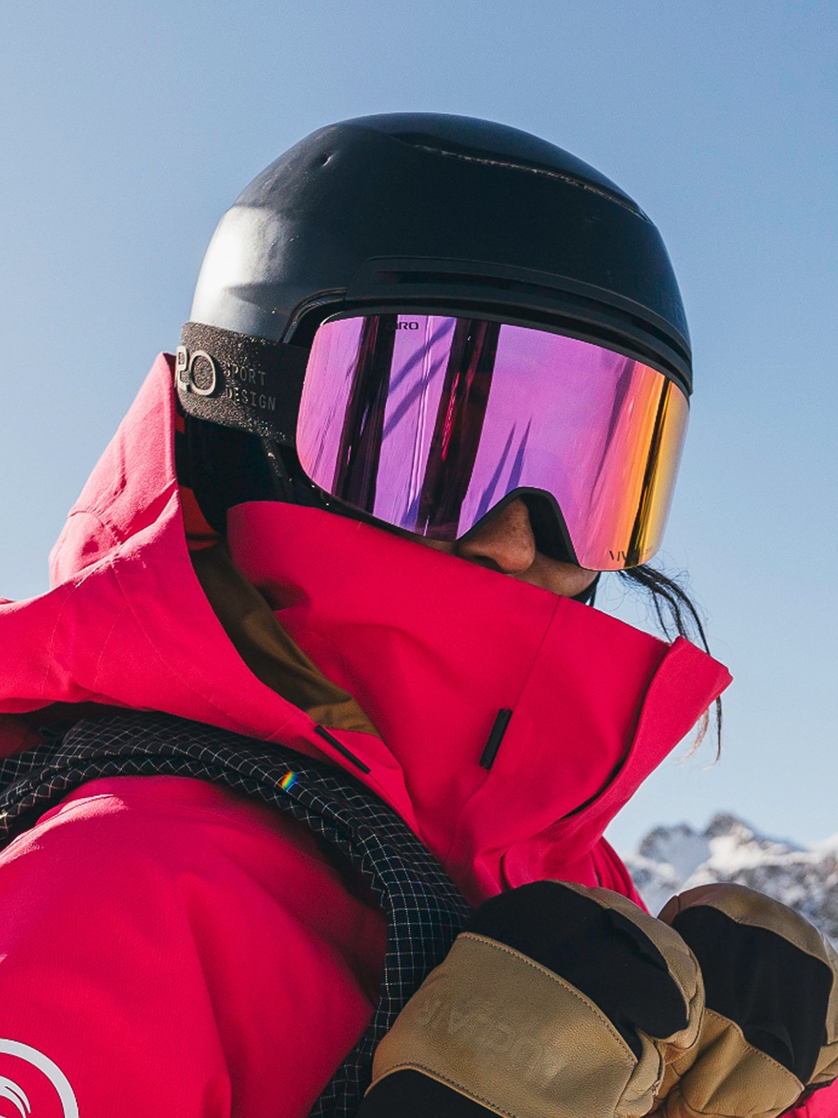 A rider in a pink kit, reflective purple goggles, and a black helmet.