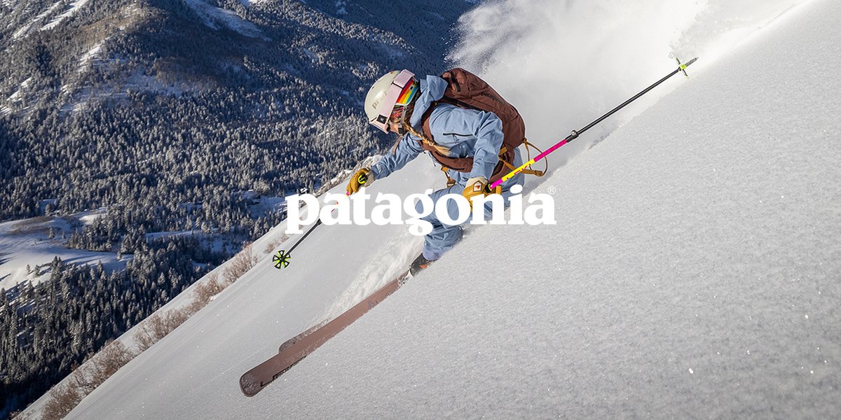 A skier walks between two large boulders. The word “Salomon” is over them.