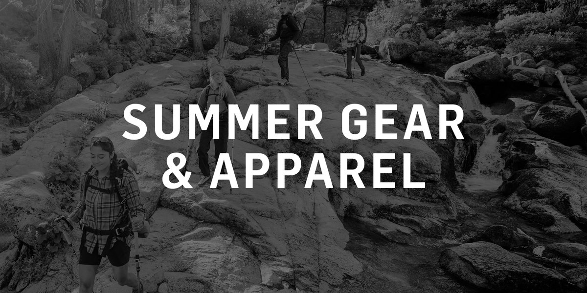 Three hikers with trekking poles pick their way across a broad granite slab surrounded by boulders and conifers.