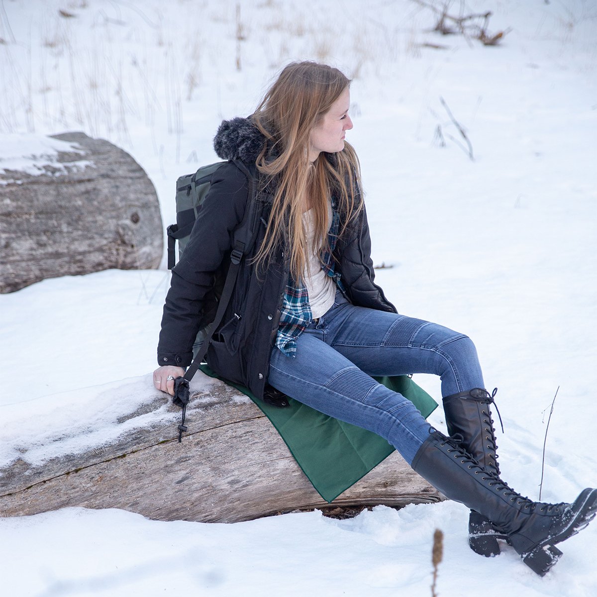 Person sitting on Coalatree Microfiber Towel layed out on top of rock surrounded by snow.