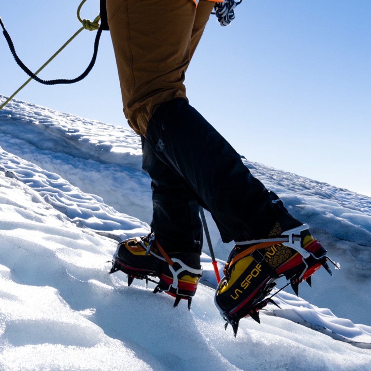 A man treks up a snowy incline, wearing Helium Gaiters. 