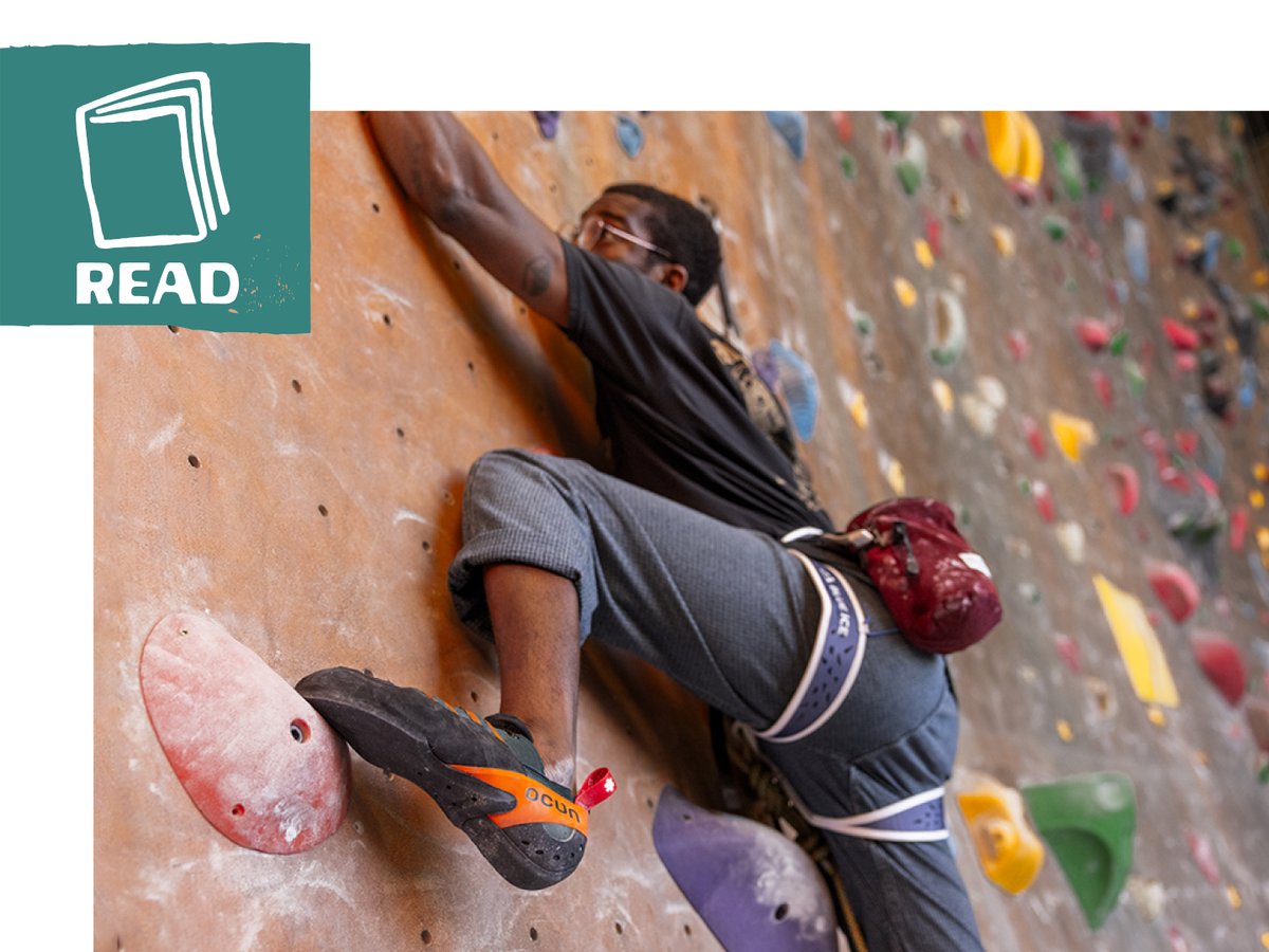 A climber does a high step on an indoor bouldering slab wall.