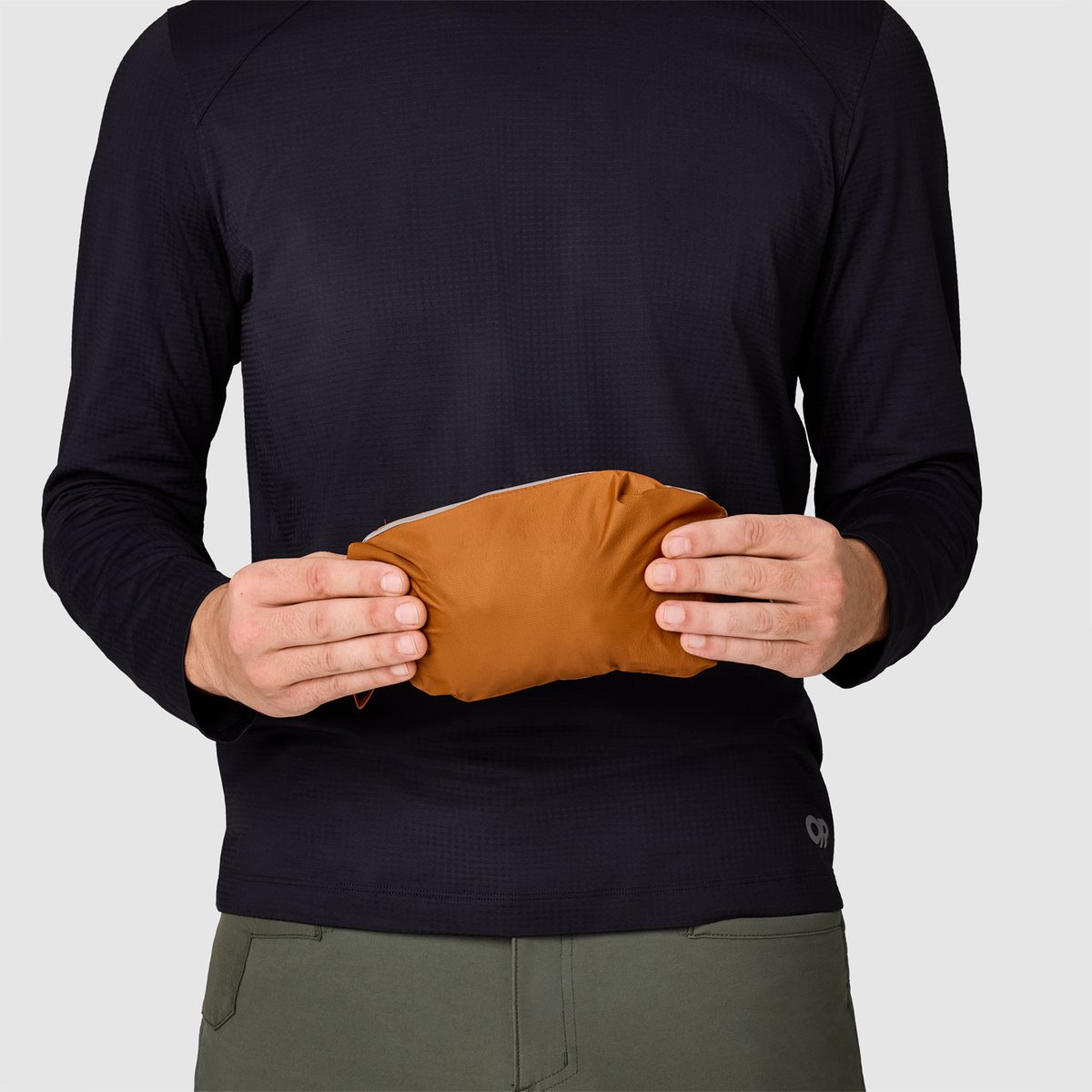 A person holds a packed Helium jacket, showcasing how small the item packs down