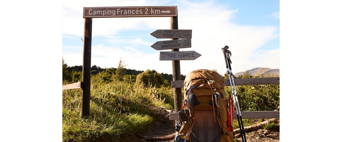 A backpacking bag rests on a wooden fence.