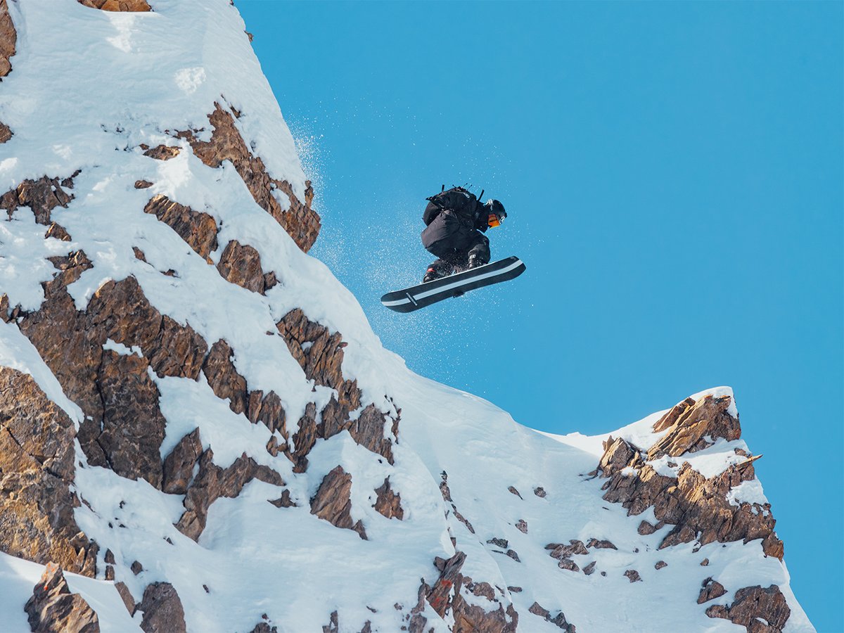 Snowboarder wearing Backcountry kit sending off a steep mountain ridgeline