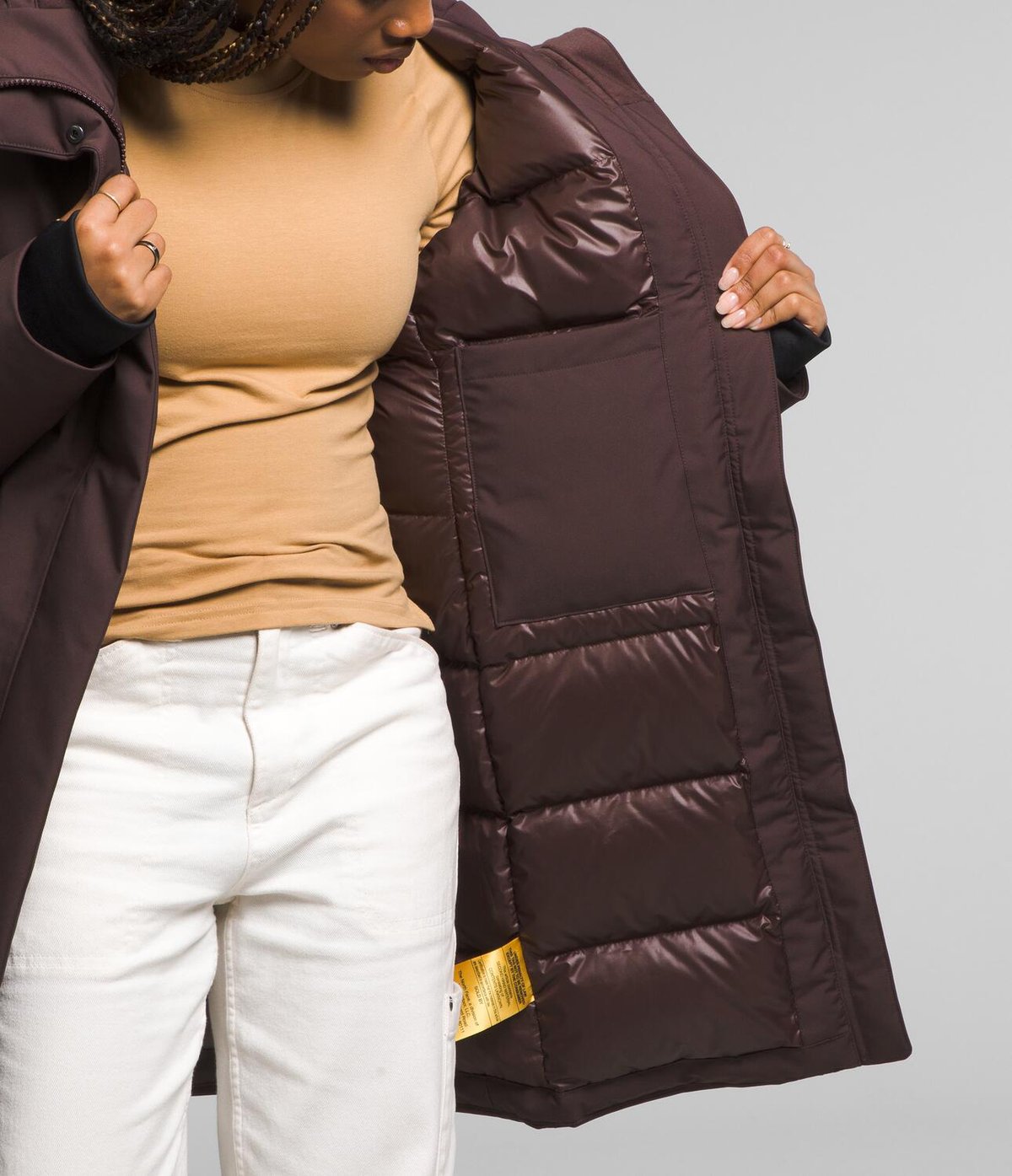 A woman showcases the interior pockets of the Arctic Down Parka