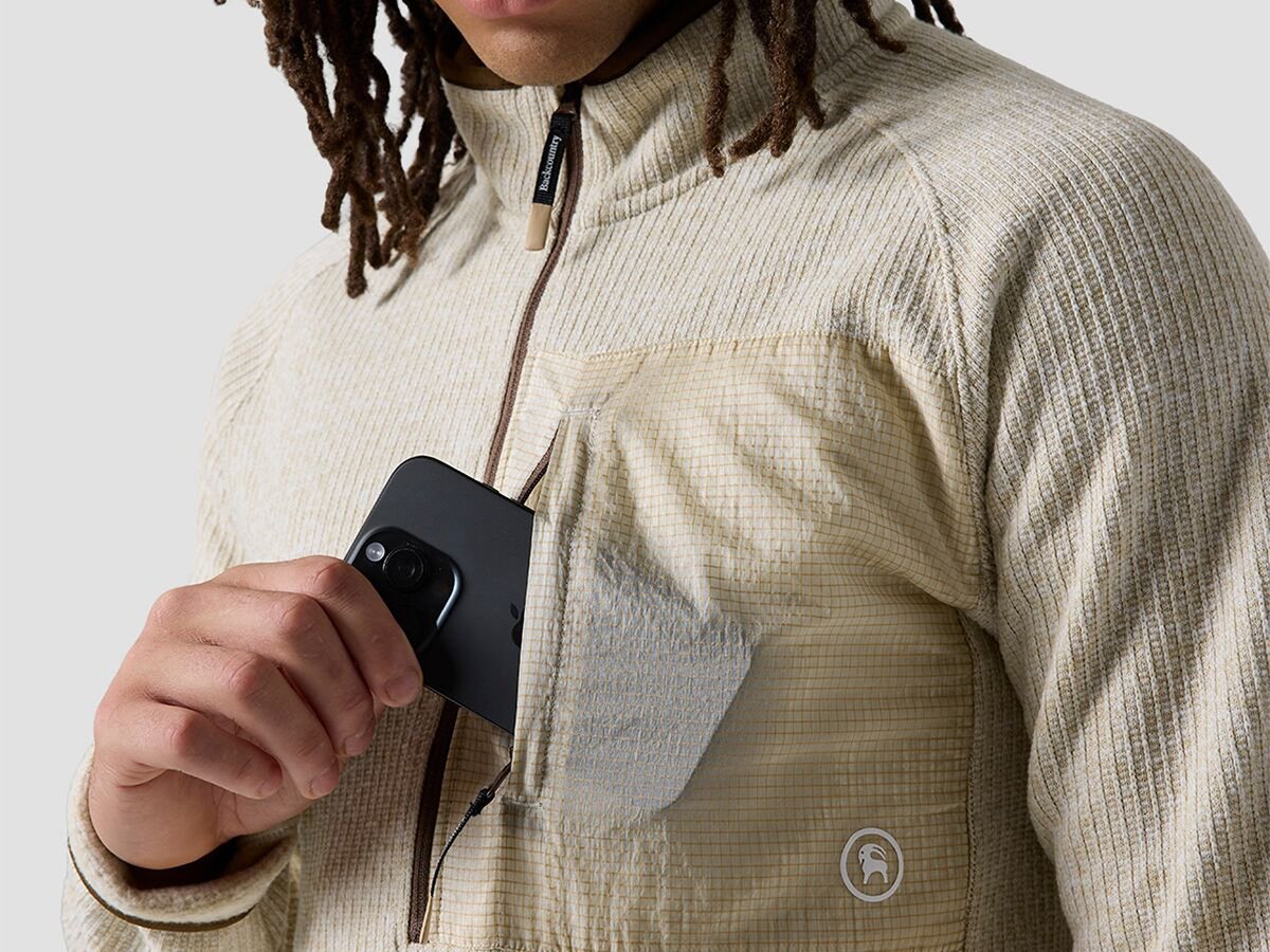 Model holding placing cell phone into zippered chest pocket.
