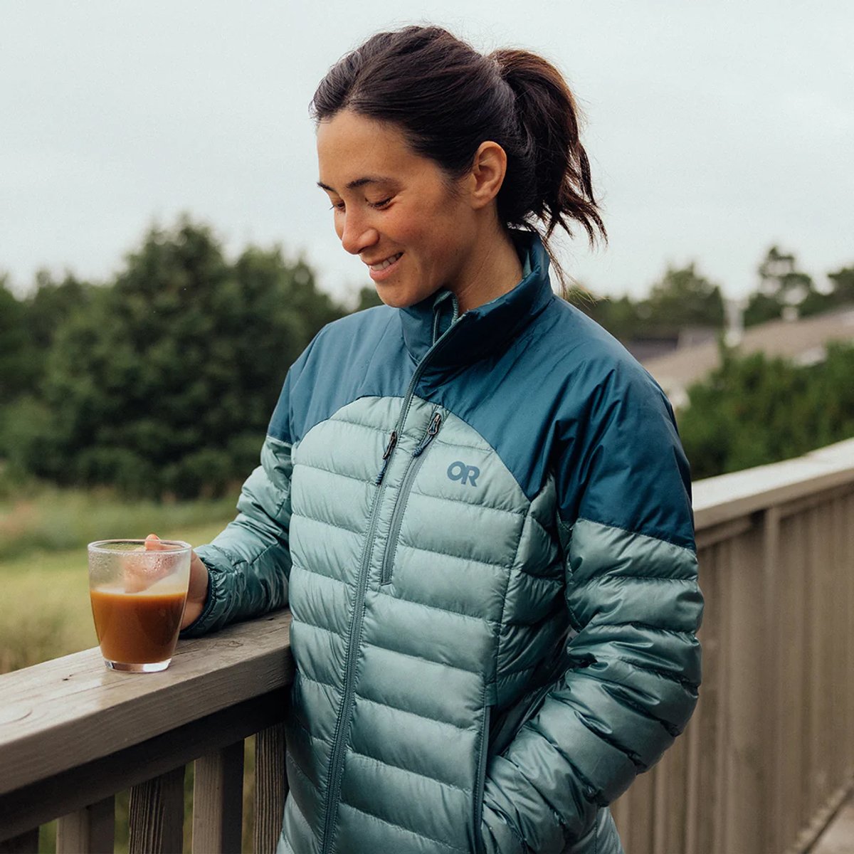 A woman wears a Helium Down jacket while holding a coffee cup