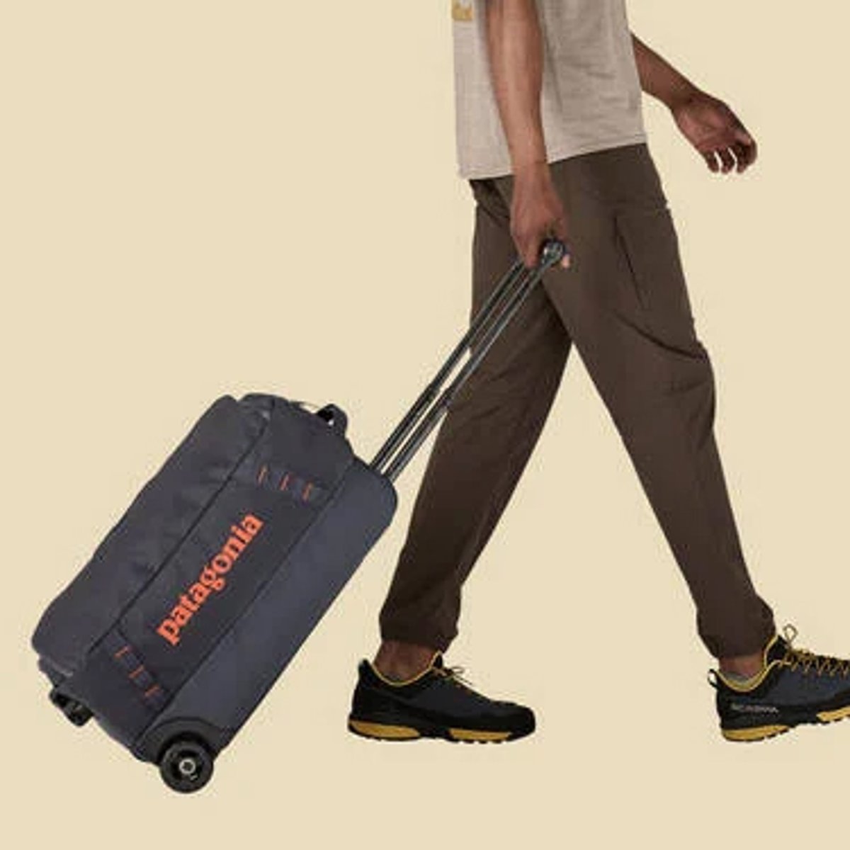 A person walks while rolling a Black Hole Wheeled Duffel 40L behind them.