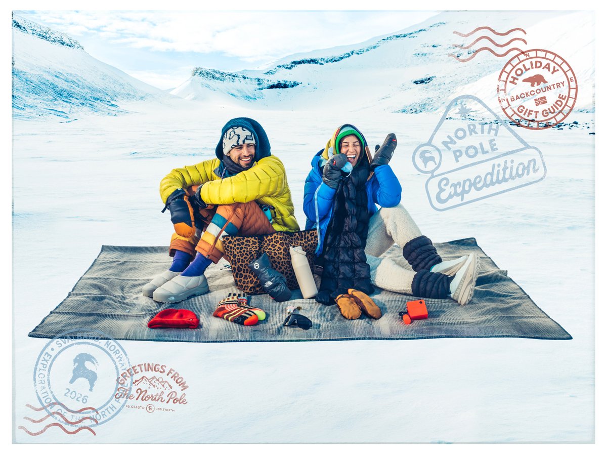 Two people laughing on a blanket in a snowy valley, with winter gear laid out in front of them, with “Holiday Backcountry Gift Guide” stamp.