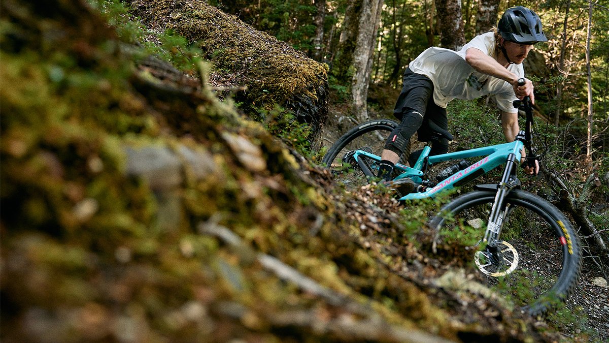 Rider riding fast downhill over technical terrain on the Nomad bike.