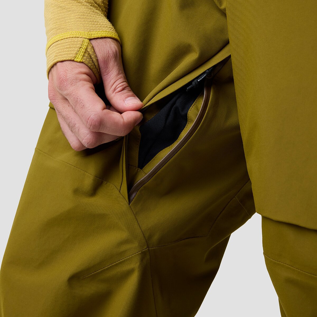 Person wearing Cottonwoods bibs opening zippered inner-thigh vent.