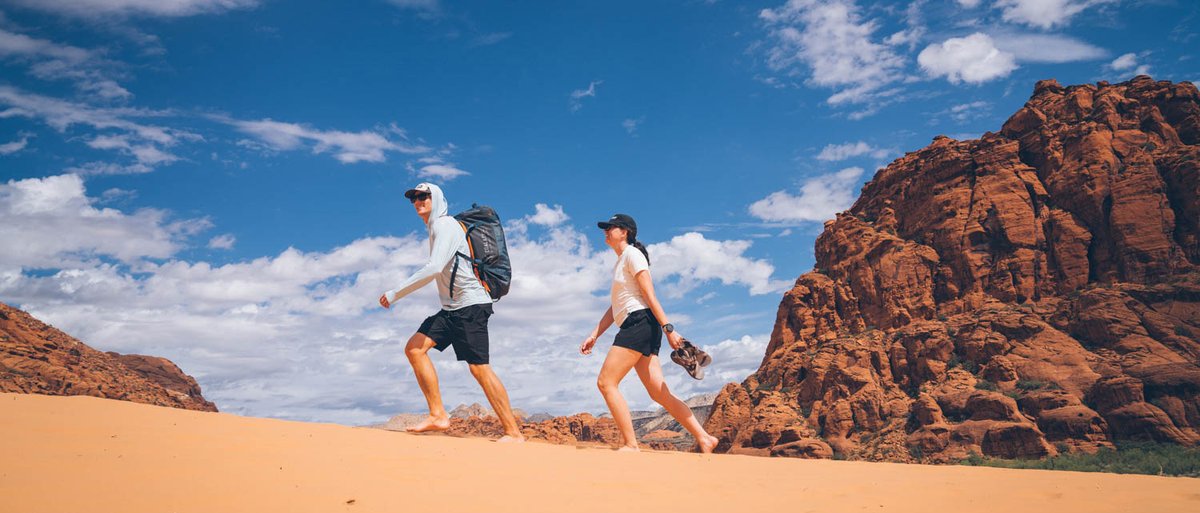 Two people hiking trhough thedesert and the first is wearing Coalatree Quest duffel as a backpack.