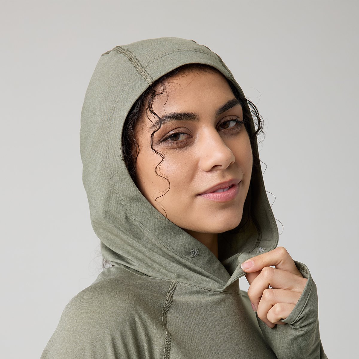 Person wearing Backcountry Tahoe Pro LT sun hood showing small clear snap at base of hood front neck opening.