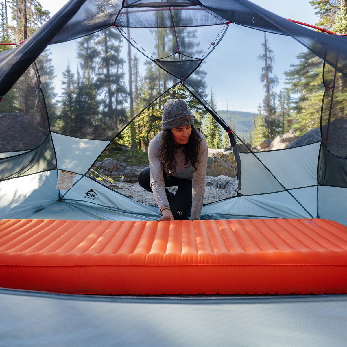 A backpacker inflates her NeoLoft sleeping pad inside her ultralight tent.