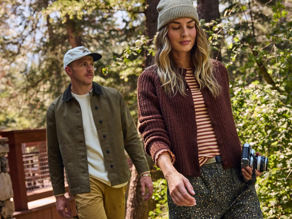 Two people walk through the woods.