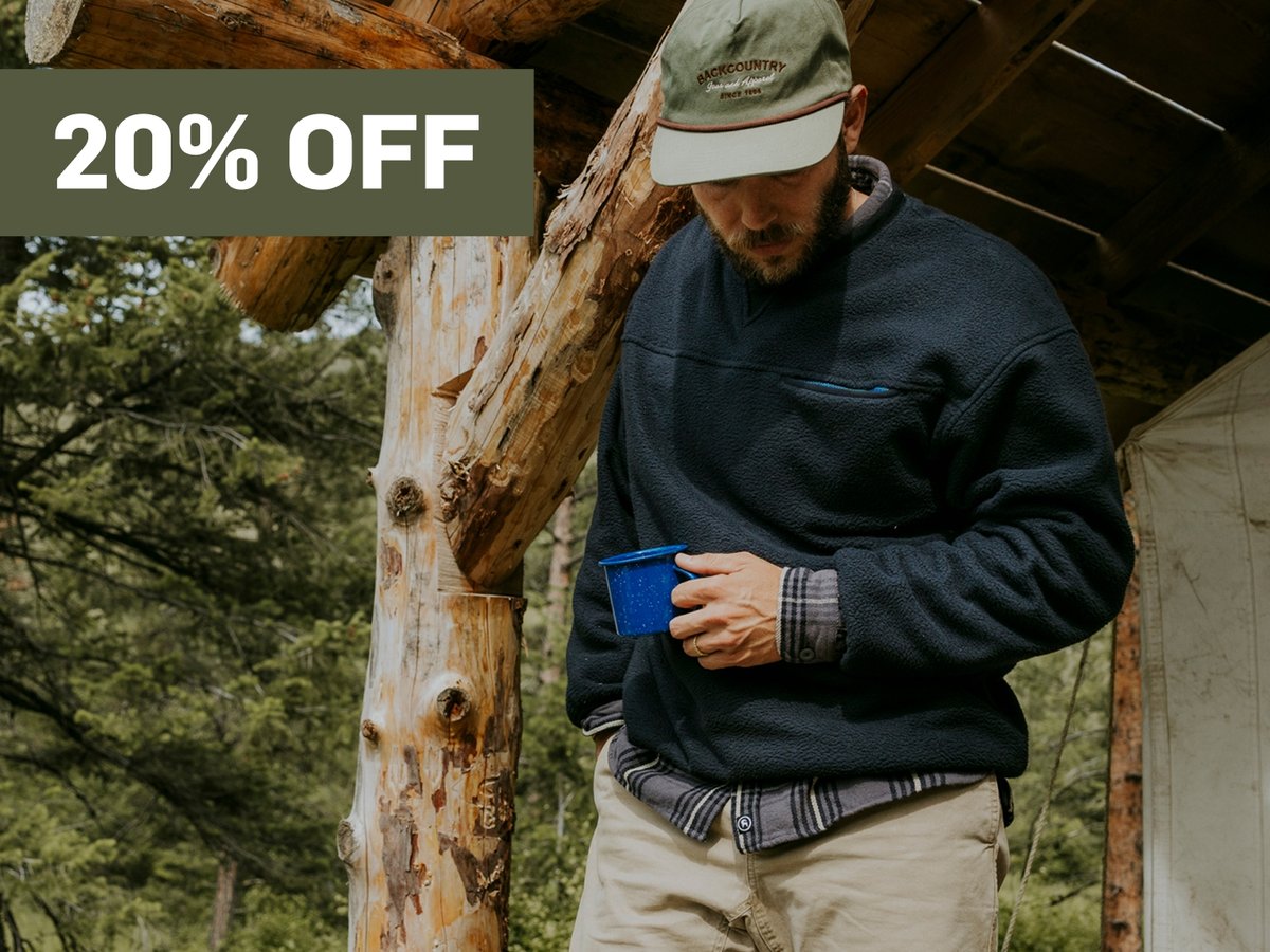 A man holds a blue cup.  A promotional flag says 20% off in the top right corner.