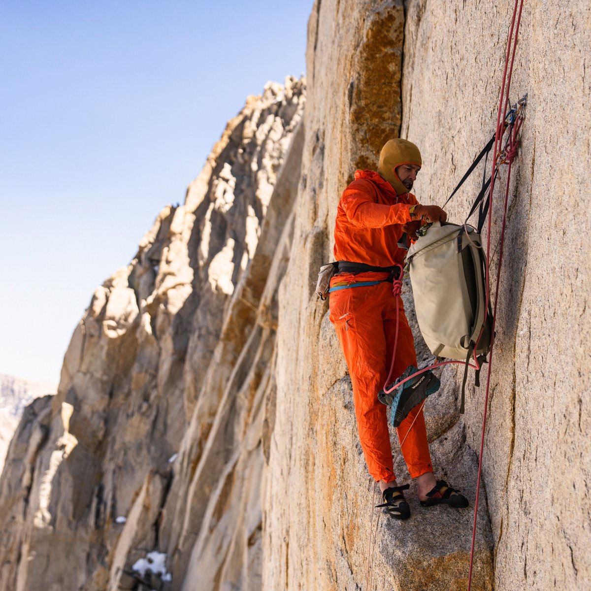 Climber accesing gear haul bag on teh wall.