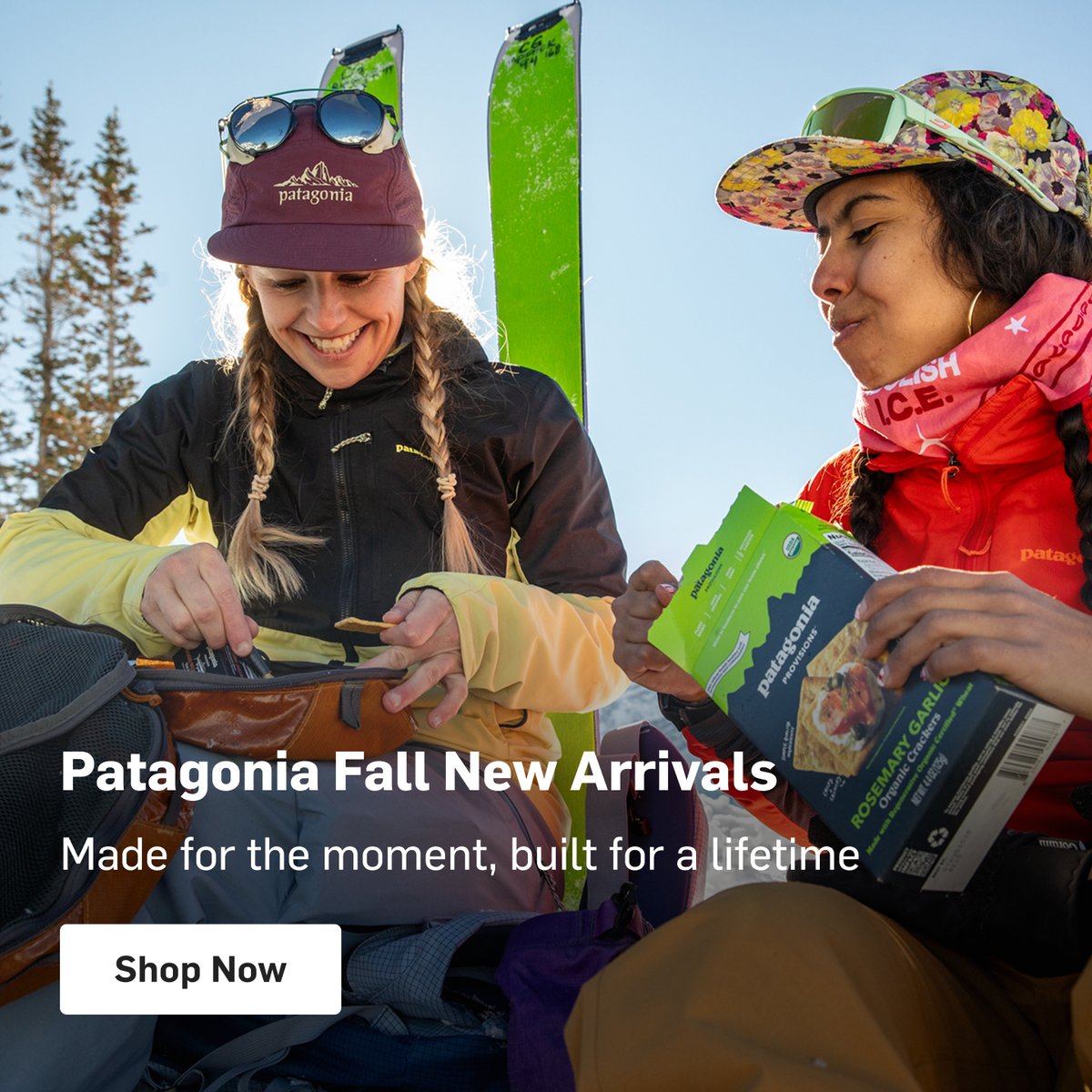 Two skiers taking a snack break in the snow, sharing Patagonia Provisions snacks in Patagonia outerwear. Patagonia Fall New Arrivals.