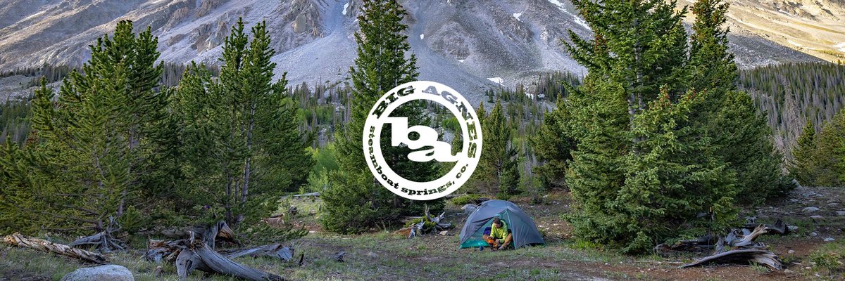 Two alpinists wearing tech hoodies, shorts, hiking boots, and running vests scale a bouldery ridge. Centered is the Patagonia logo.