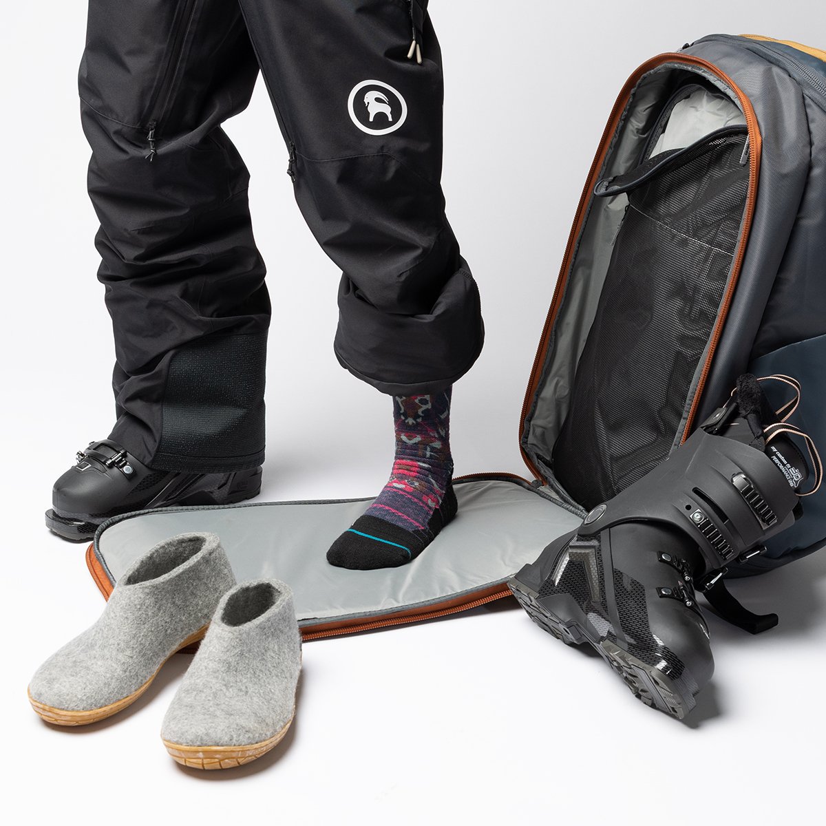 Person wearing ski pants standing on changing mat to remove ski boot.