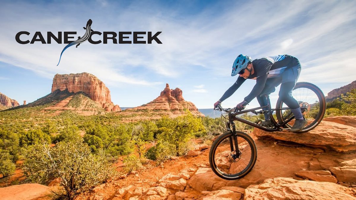 Mountain biker in blue helmet riding on red desert trail with iconic red rock formations in background near Sedona, Arizona.