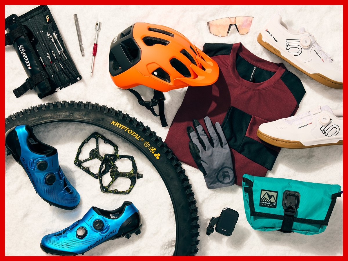 Bike gear arranged on snow, including S-fire and 5.10 shoes, Kryptotal tires, a POC helmet, and lots of bike tools.