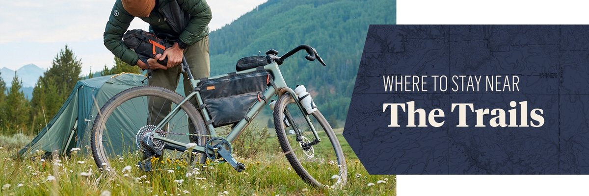 A rider packs their bike bag. The text overlay reads: Where to stay near the trails.