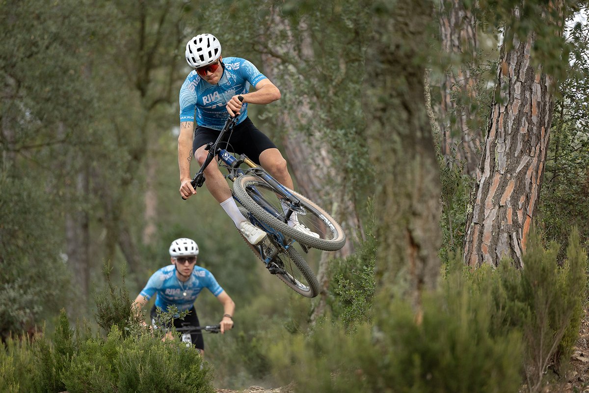 Rider sending the Pivot Mach 4 SL cross-country mountain bike on forest singletrack