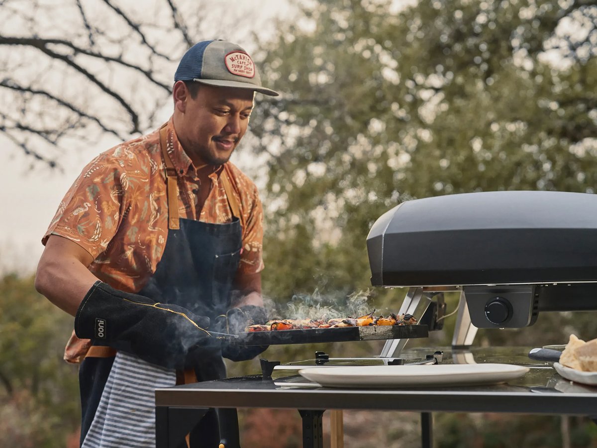 A man makes food in a backyard pizza oven.