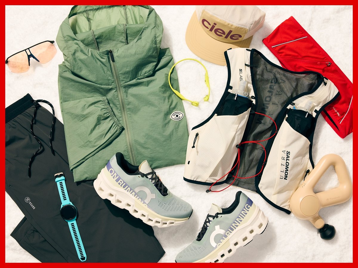 Running gear displayed on snow: On running shoes, a Salomon running vest, Ciele hat, Garmin watch, and various other fitness accessories.