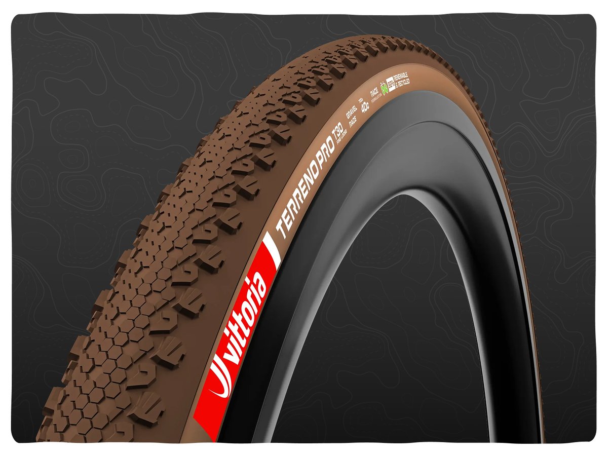 A Vittoria gravel tire with a brown rubber compound, an octagonal slick center tread, and stepped shoulder knobs. 