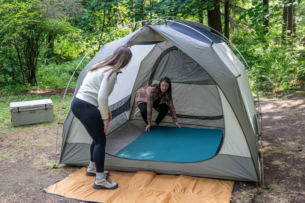 Campers placing the MegaMat in a tent.