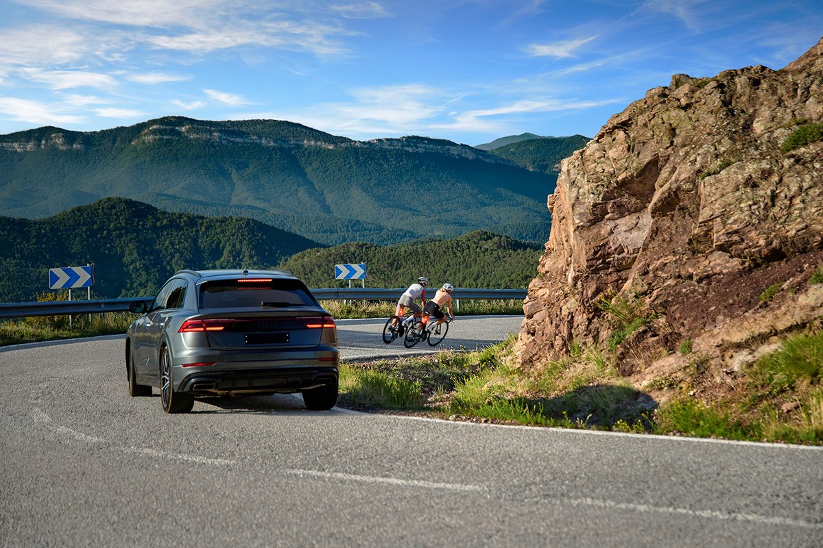 Cyclists riding mountain road with illuminated rear bike lights near vehicle traffic