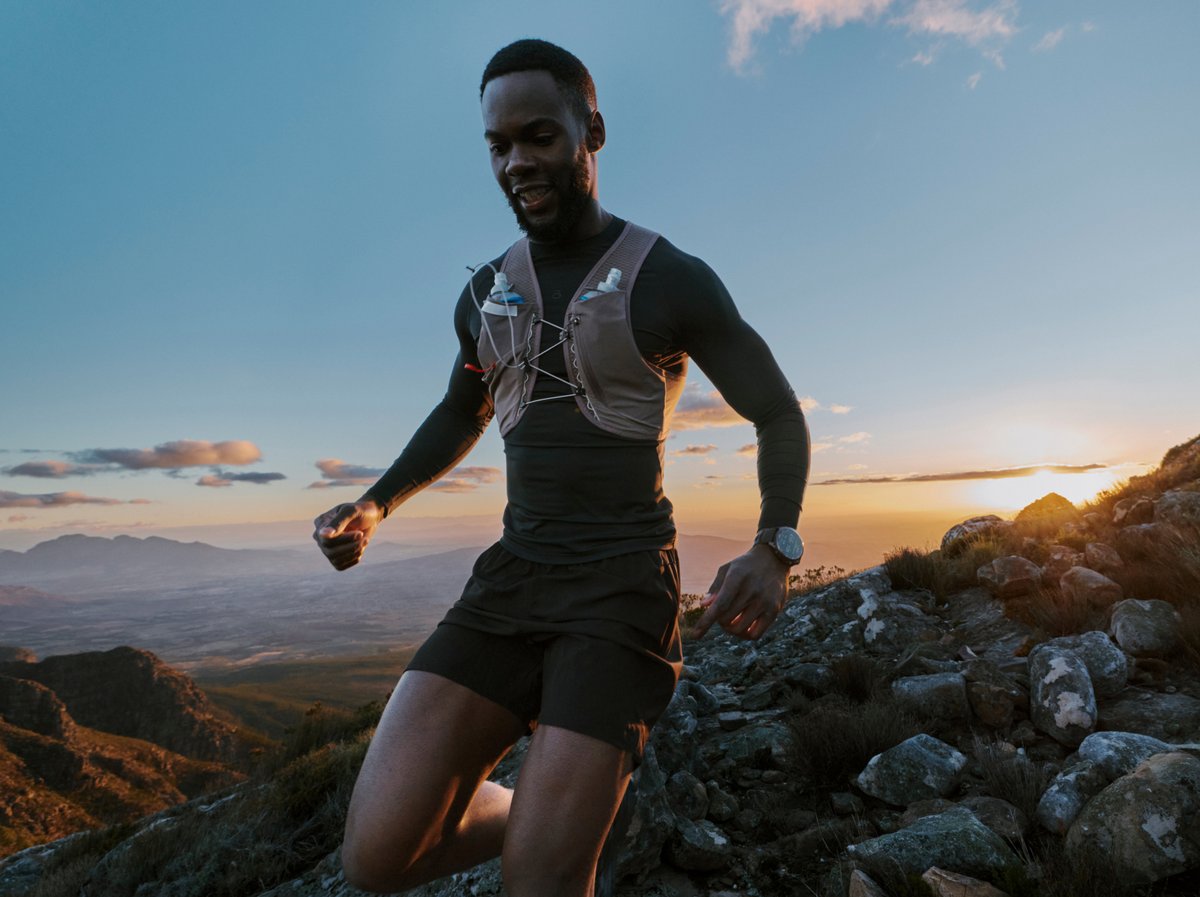 Trail runner on a mountain ridge at sunset wearing a running vest, alongside a product shot of the Garmin Fenix 9 in Titanium/Pebble Grey.