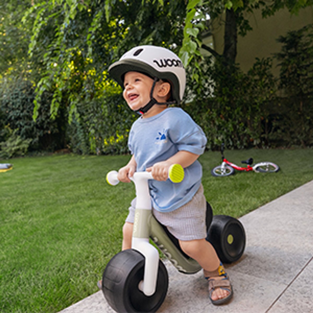 Small kid wearing helmet riding wow bike down a driveway.