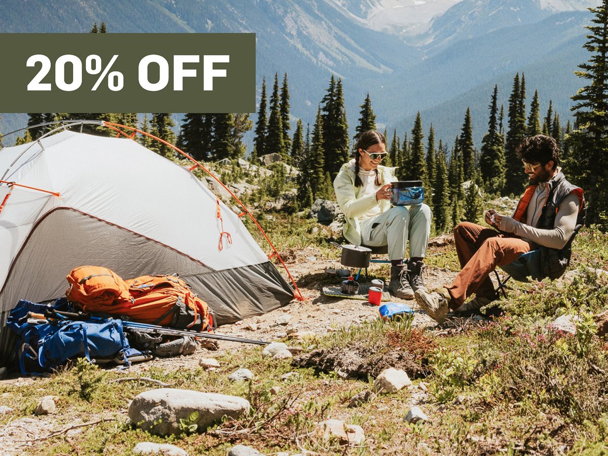 People people sit next to a tent. A promotional flag says 20% off in the top right corner.